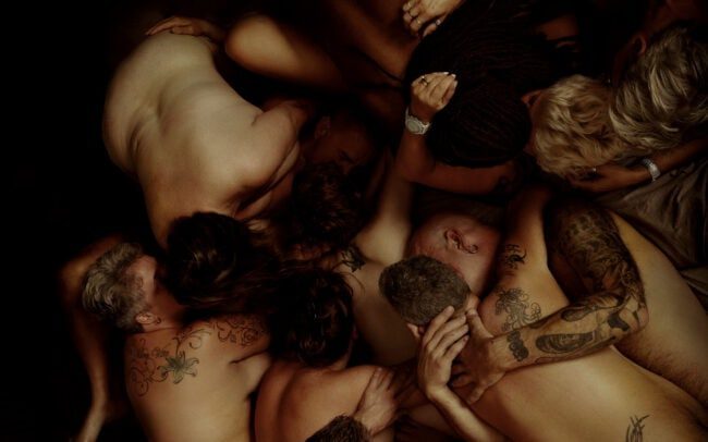 Collective Embrace — fine art photography by Menno van der Meulen. Description: A low-key fine art composition of intertwined nude bodies forming a single sculptural mass; themes of intimacy, trust and connection.