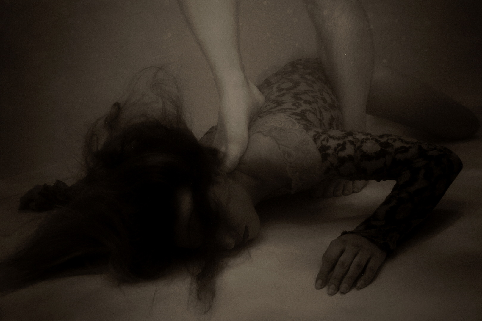Female body submerged and pinned underwater, face pressed down and hand gripping her hair, in a dark erotic scene exploring control, submission and restraint by Menno van der Meulen.
