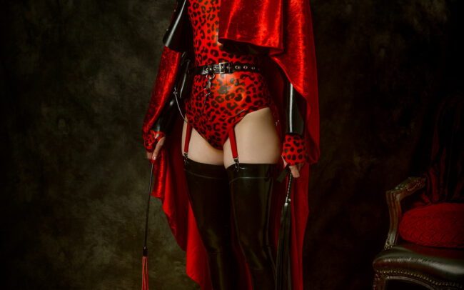 Red Silence by Menno van der Meulen. Masked figure in red costume and boots standing in a dark studio, Berlin, 2025.