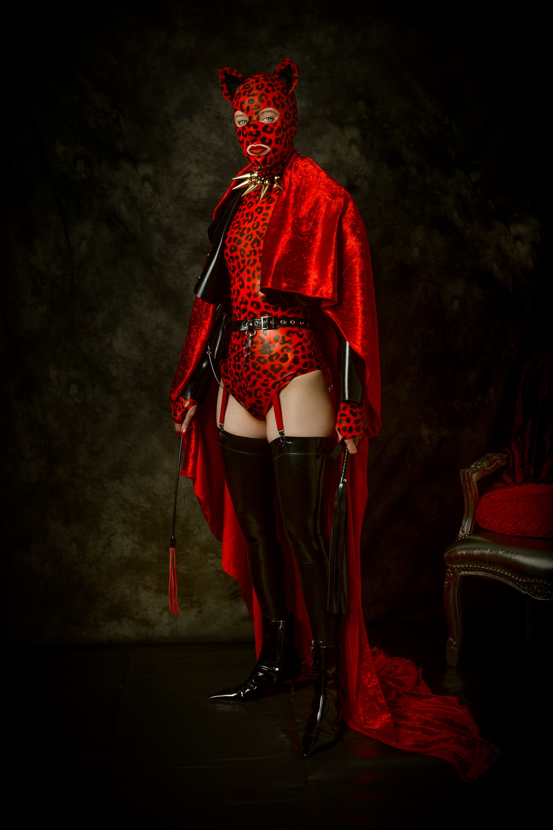 Red Silence by Menno van der Meulen. Masked figure in red costume and boots standing in a dark studio, Berlin, 2025.